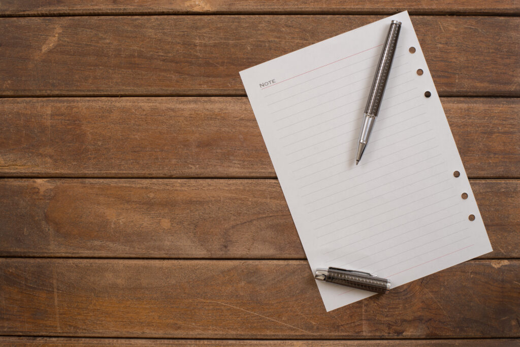 Notepad with pen on office wooden table.