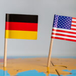Small flags of Germany and the USA on a wooden stick fixed on the globe