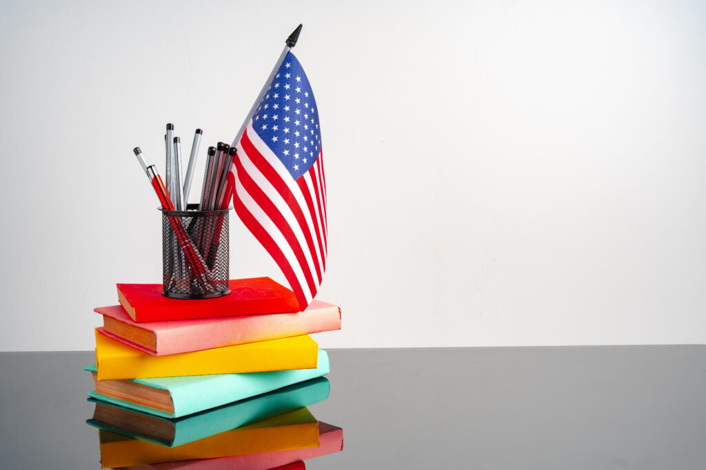 USA flag with pile of colorful books on black table