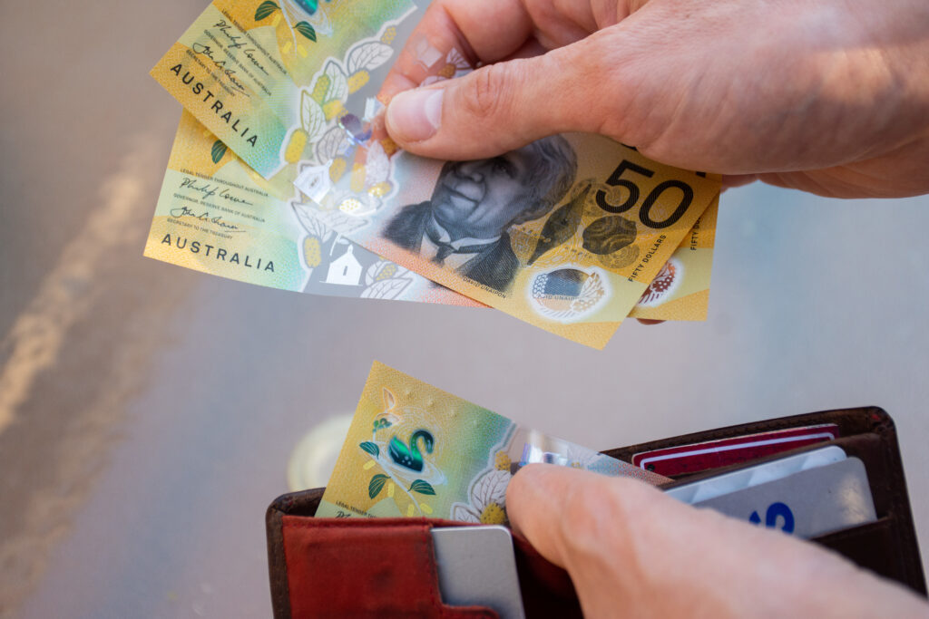 Hands holding wallet with australian dollars and make a payment – coronavirus finance struggle concept.