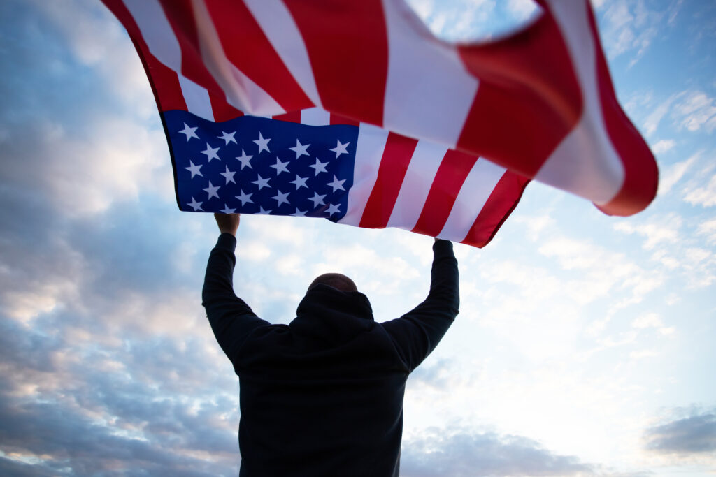 Man holding a waving american USA flag.